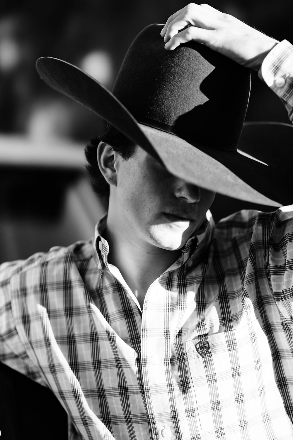 Black and white shot of a senior boy covering most of his face with his cowboy hat, Casmalia, CA.