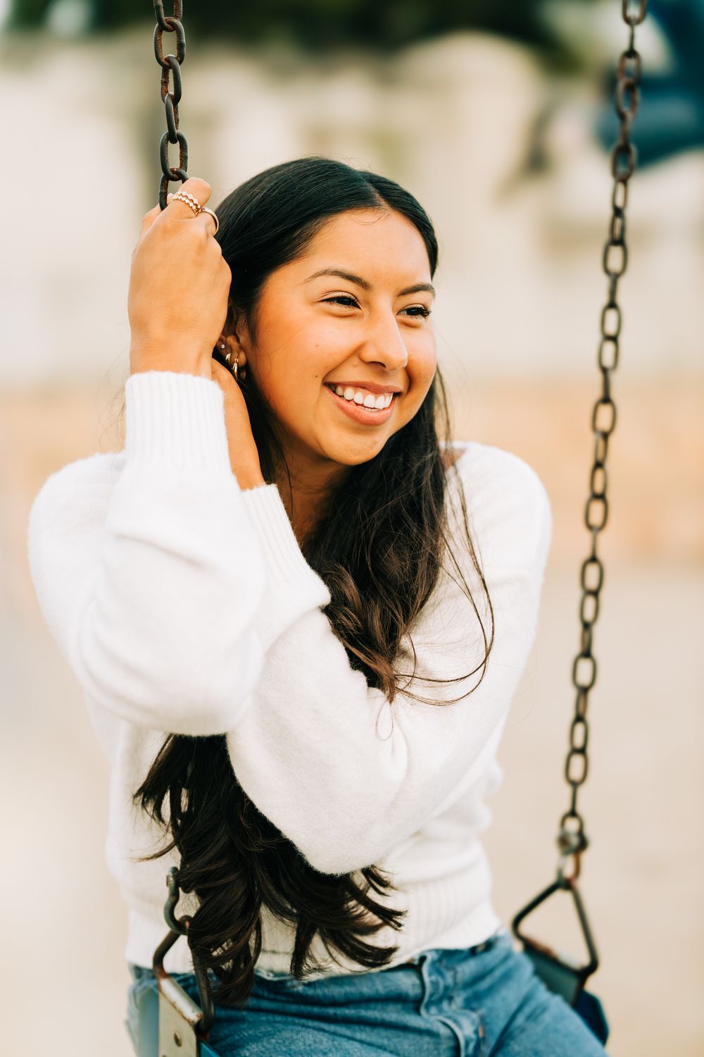 Senior girl sitting on a swing holding the chain, Pismo Beach, CA