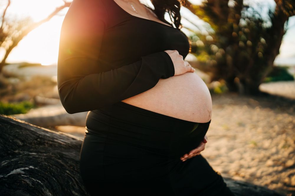 Maternity session at the Monarch Butterfly Preserve in Pismo Beach California, mama's baby bump in black dress.