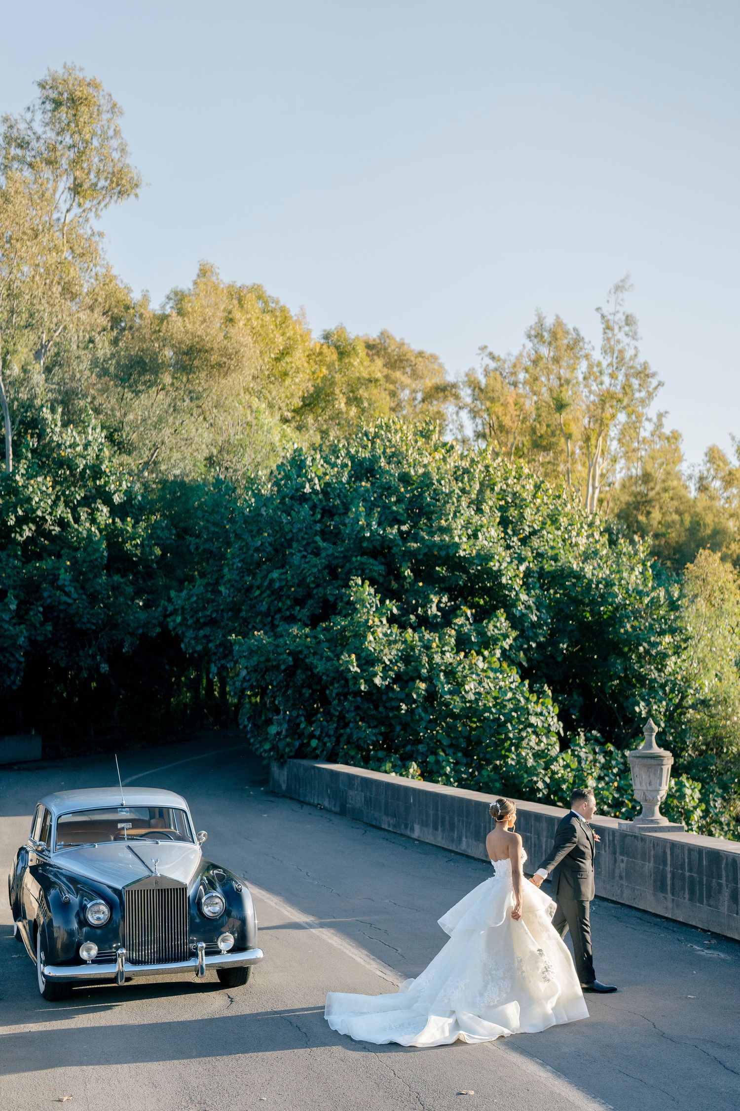 Elegant wedding portraits with vintage luxury cars against a scenic outdoor backdrop.