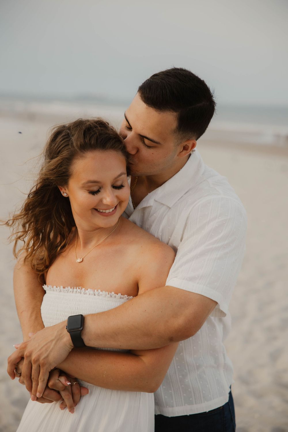 Intimate beach portraits of couple in white clothing sharing tender moments.