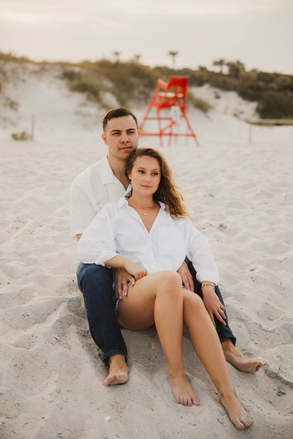 Casual beach couple photos with couple relaxing on white sand.