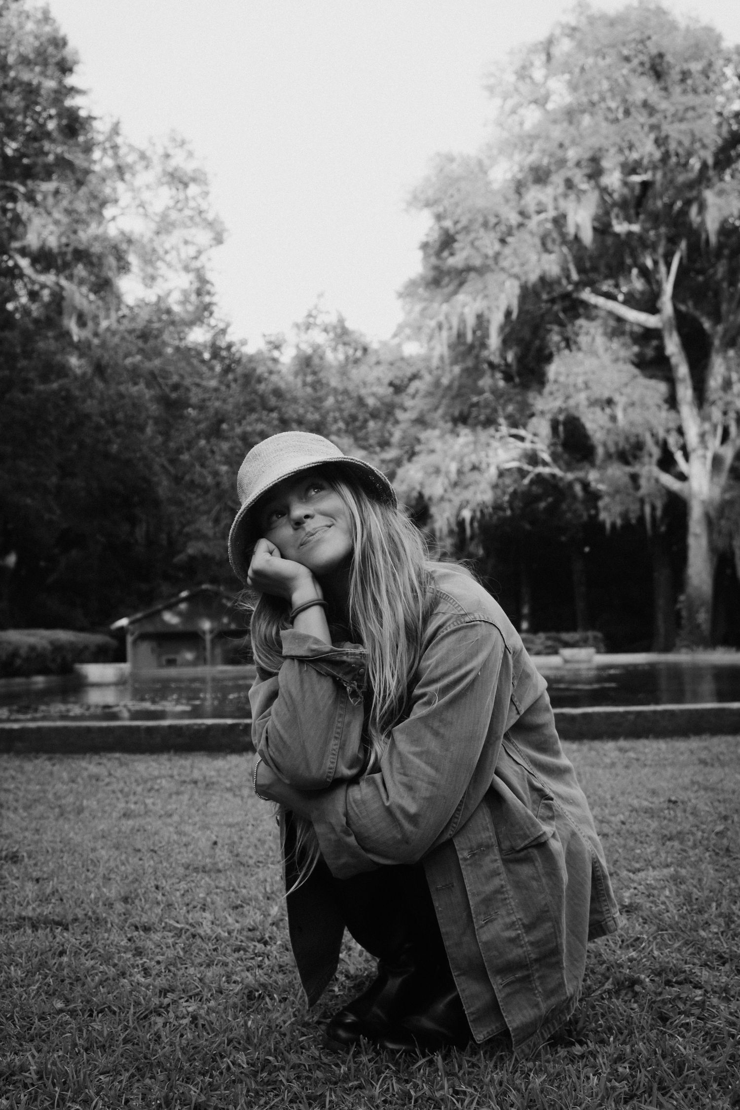 Black and white photo of someone in casual wear sitting in a park setting.