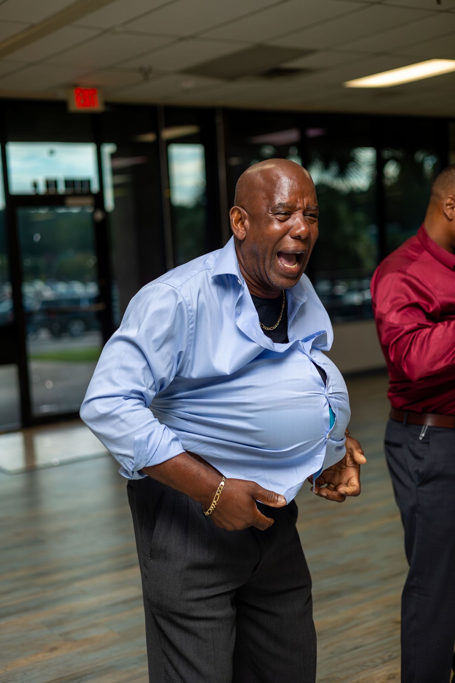 Person in light blue shirt dancing enthusiastically in an indoor space.