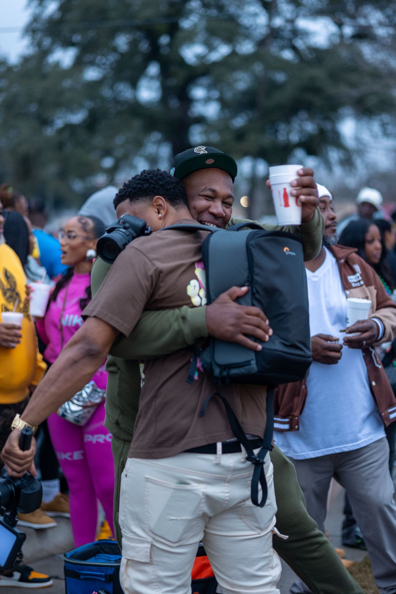 Two people share warm embrace during outdoor celebration.