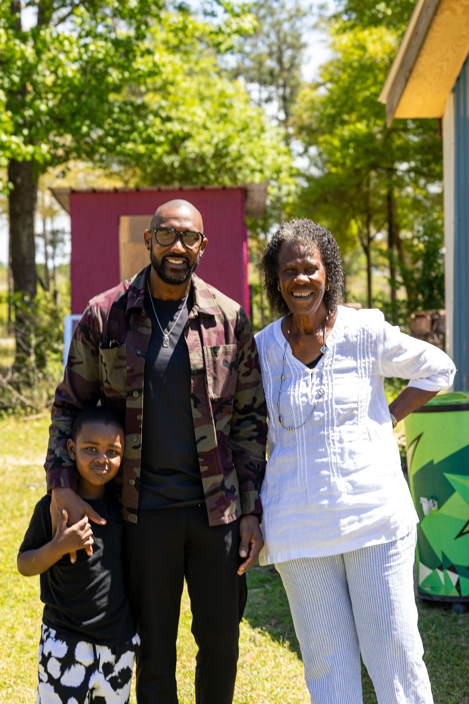 A family poses together on a sunny day outdoors in front of colorful decorations.