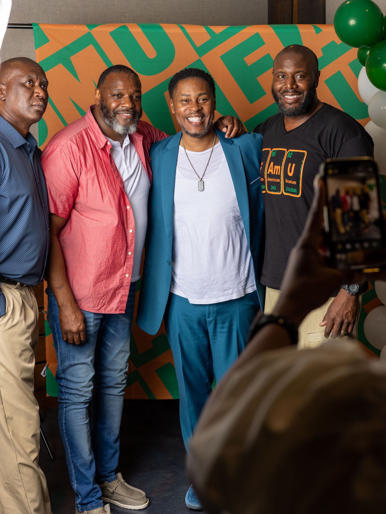 Group of friends gathered together at casual event with colorful wall art background.