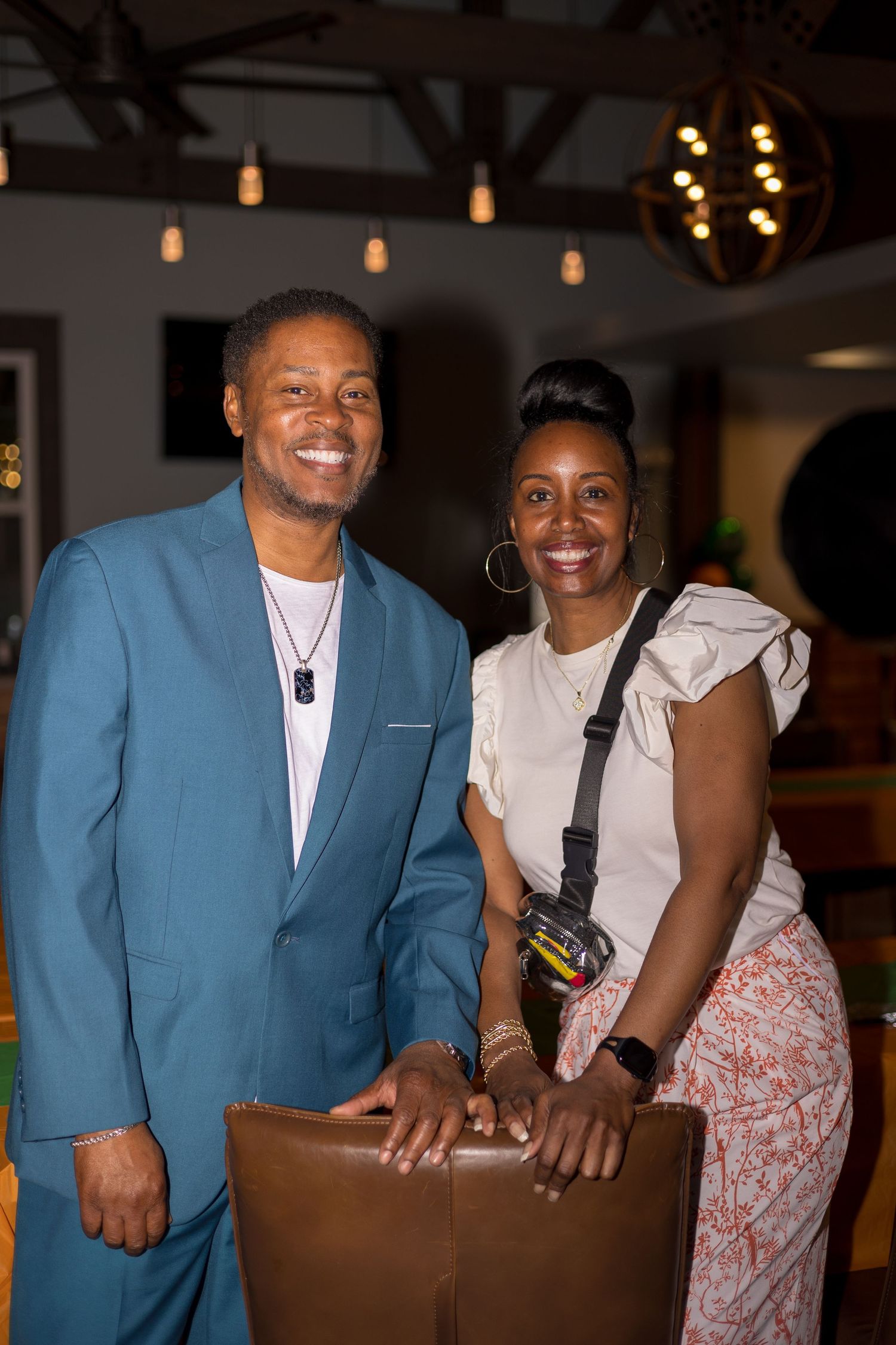 Couple posing together at indoor event space with warm lighting.