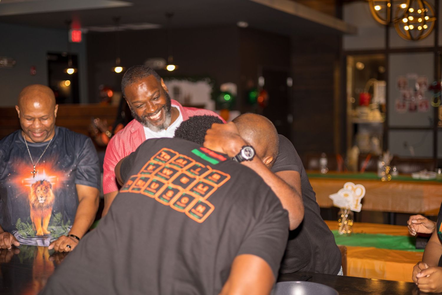 Friends laughing together during social event at dimly lit venue.