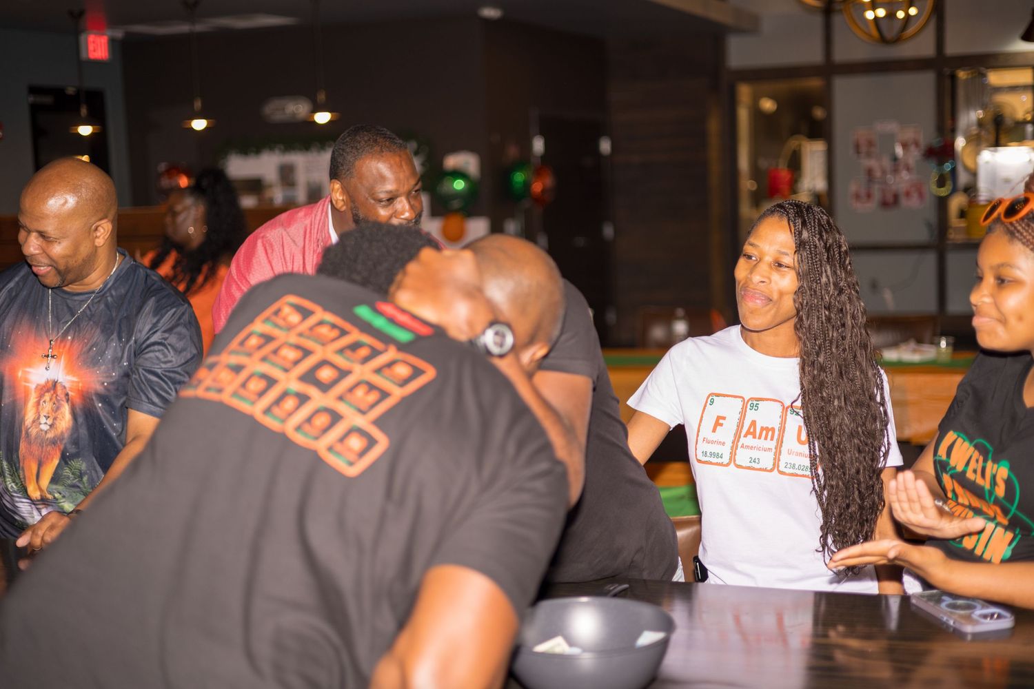 A lively social gathering shows people mingling at what appears to be a casual indoor event.