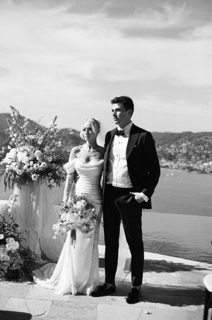 Classic black and white portrait of couple against scenic coastal backdrop.