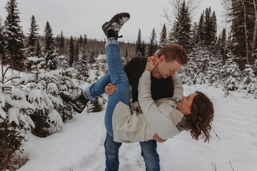 A playful winter dip pose surrounded by snow-covered pine trees.