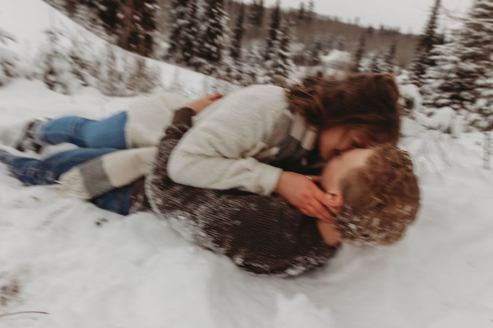 A couple playing in the snow during a winter photoshoot.