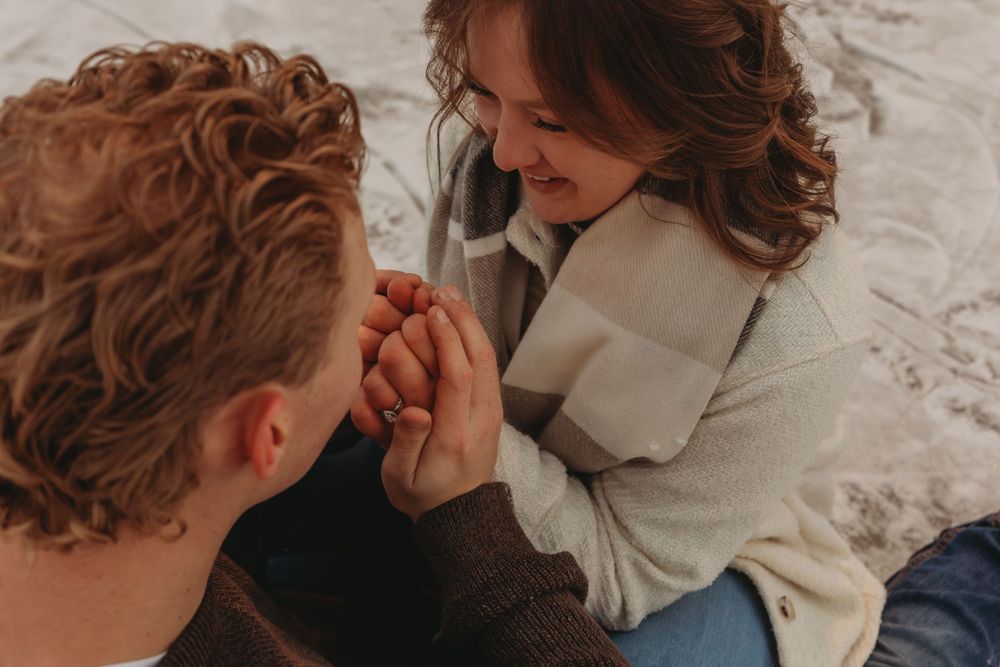Close-up of hands clasped together during an intimate winter moment.