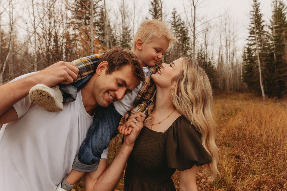 Family sharing a joyful moment together against an autumn forest backdrop.