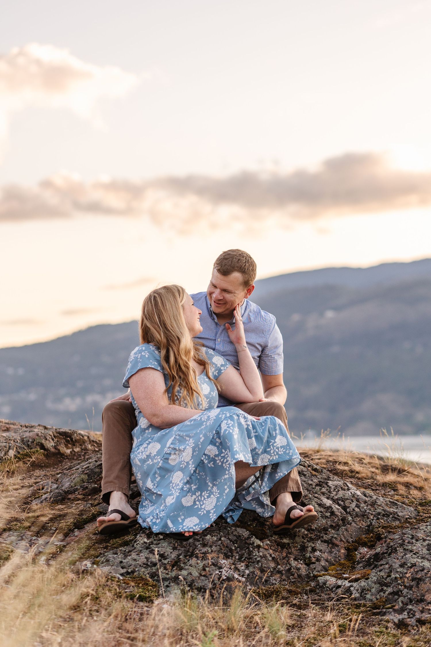 A couple shares tender moments on a rocky hilltop at sunset.
