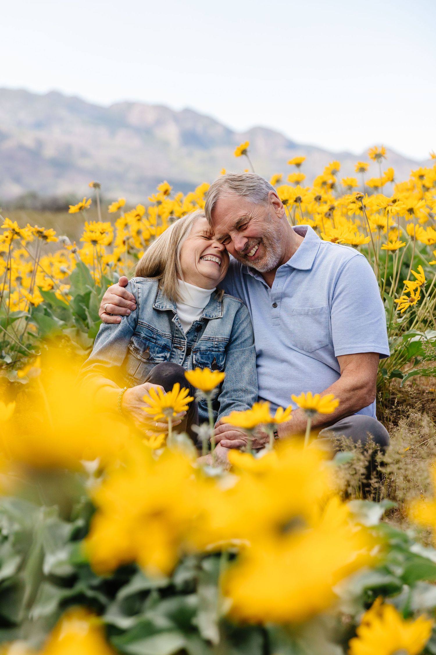 A couple shares intimate moments in a field of bright yellow sunflowers.