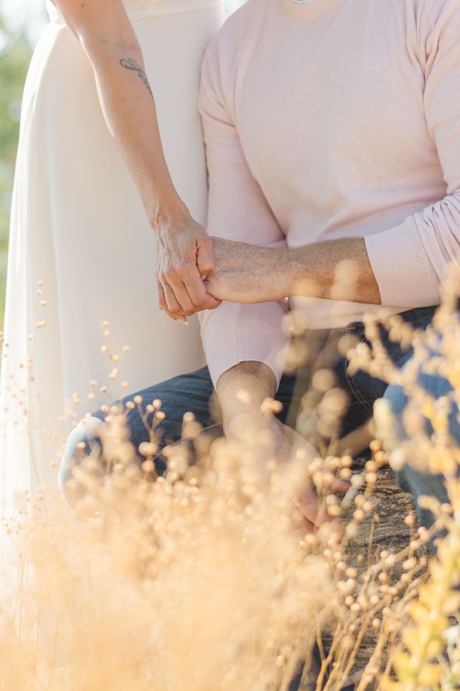 Person wearing light colored clothing stands in a field of golden dried grass at sunset.