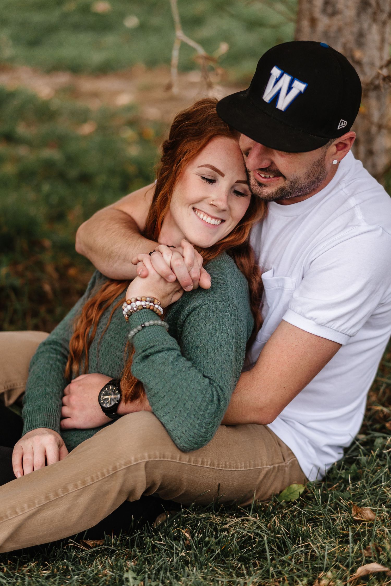 A couple relaxes together on grass during an autumn day.