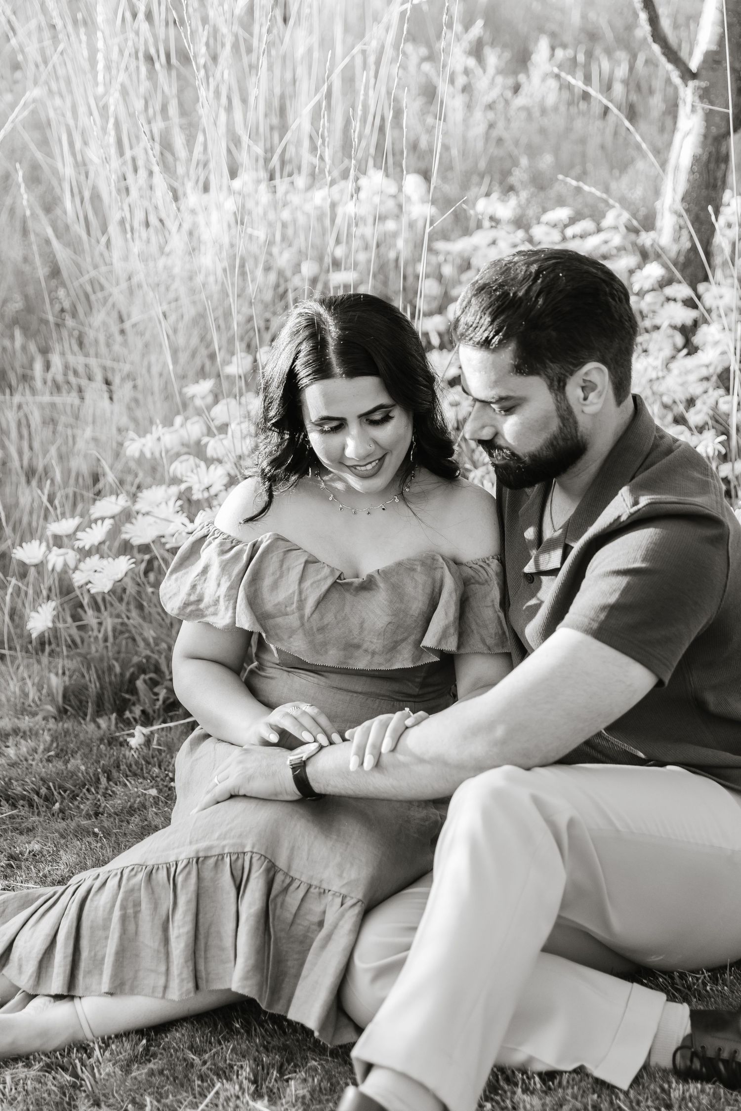 A black and white photo series captures tender moments between a couple sitting together outdoors.