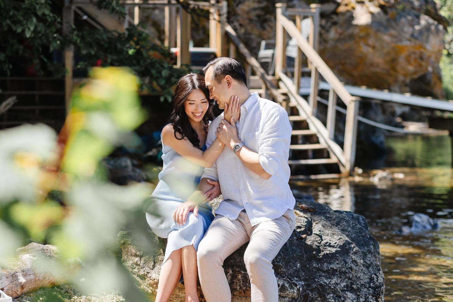 Family sits together on wooden dock by tranquil pond during golden hour outdoor photo session.