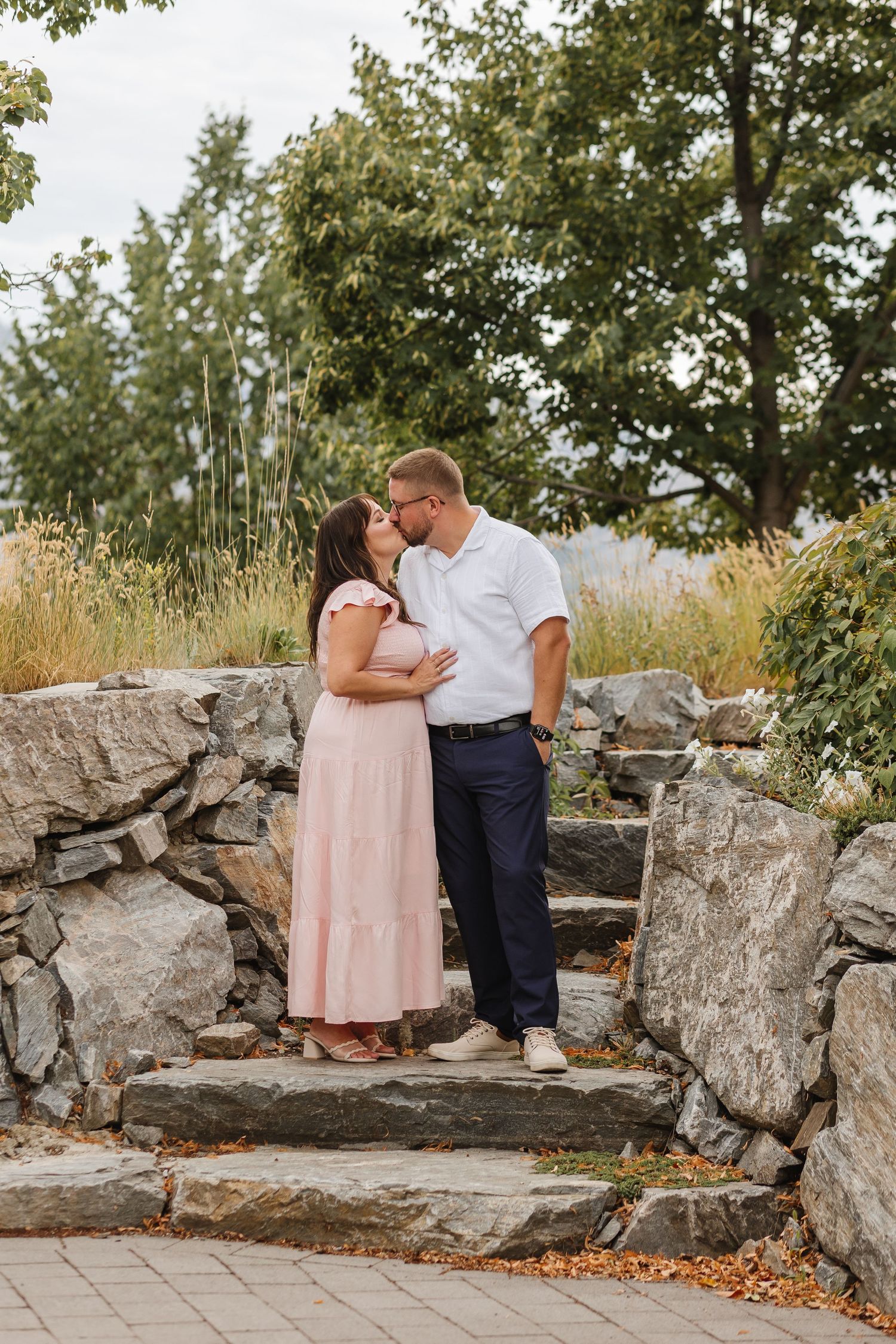 A romantic couple embraces on stone steps surrounded by autumn foliage and natural rock formations.