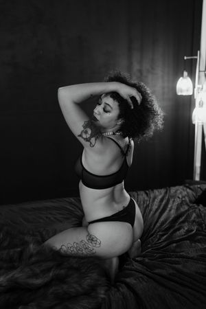 adult person posing on a bed, wearing lingerie, during a boudoir photography session