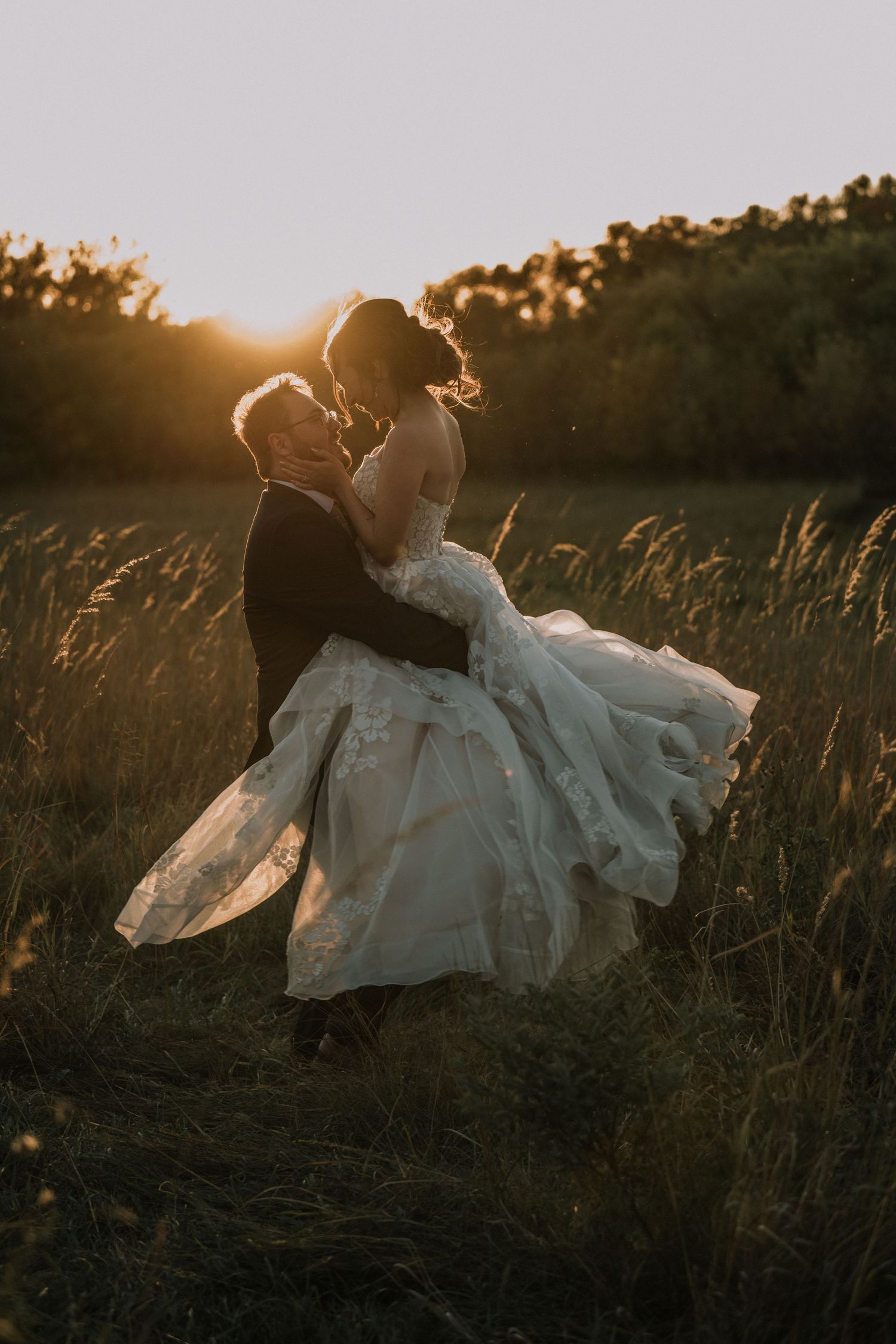 A wedding couple spinning in joy after their wedding day was over during their golden wedding day sunset.