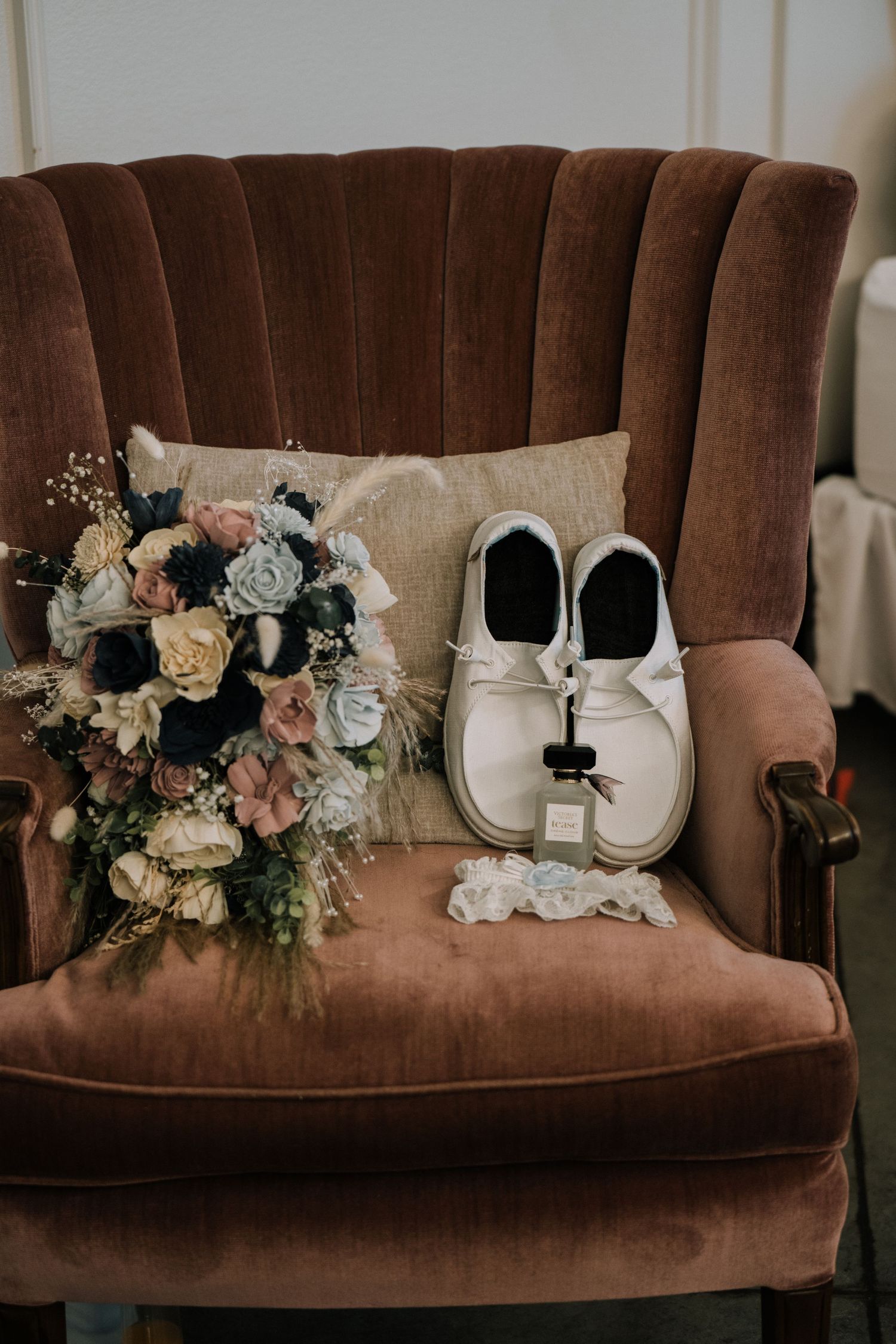 A wedding day detail photo with shoes and a romantic bouquet of roses and mixed flowers, garder and perfume.