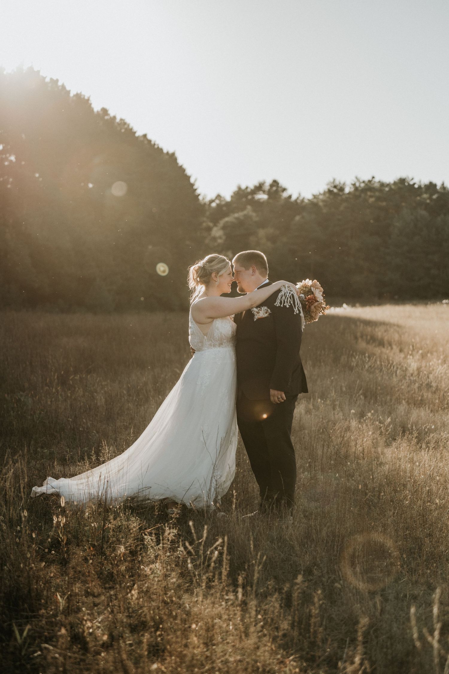 A couple poses in love during a golden sunlit meadow with a beautiful summer glow. MN wedding ND wedding SD wedding photographer