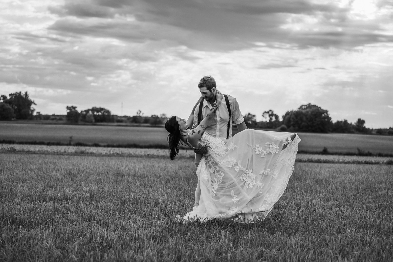 a black and white dip photo at sunset with a wedding couple in wedding outfits.