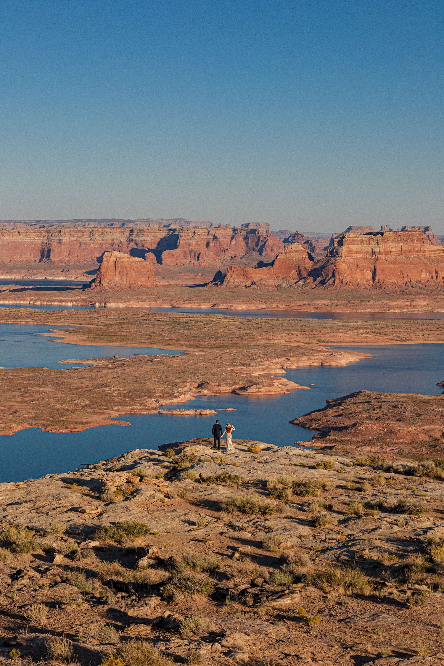 Expansive view of Lake Powell surrounded by red rock cliffs and desert landscape.