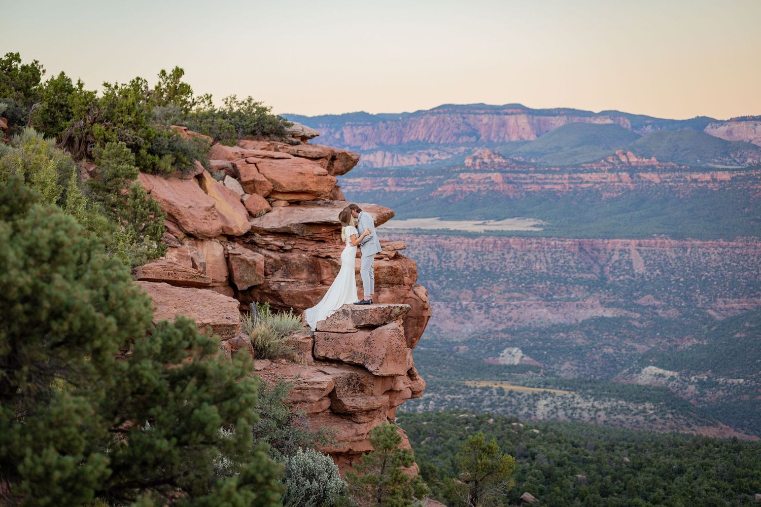 Scenic panorama of red rock formations and mountains in Sedona during golden hour.