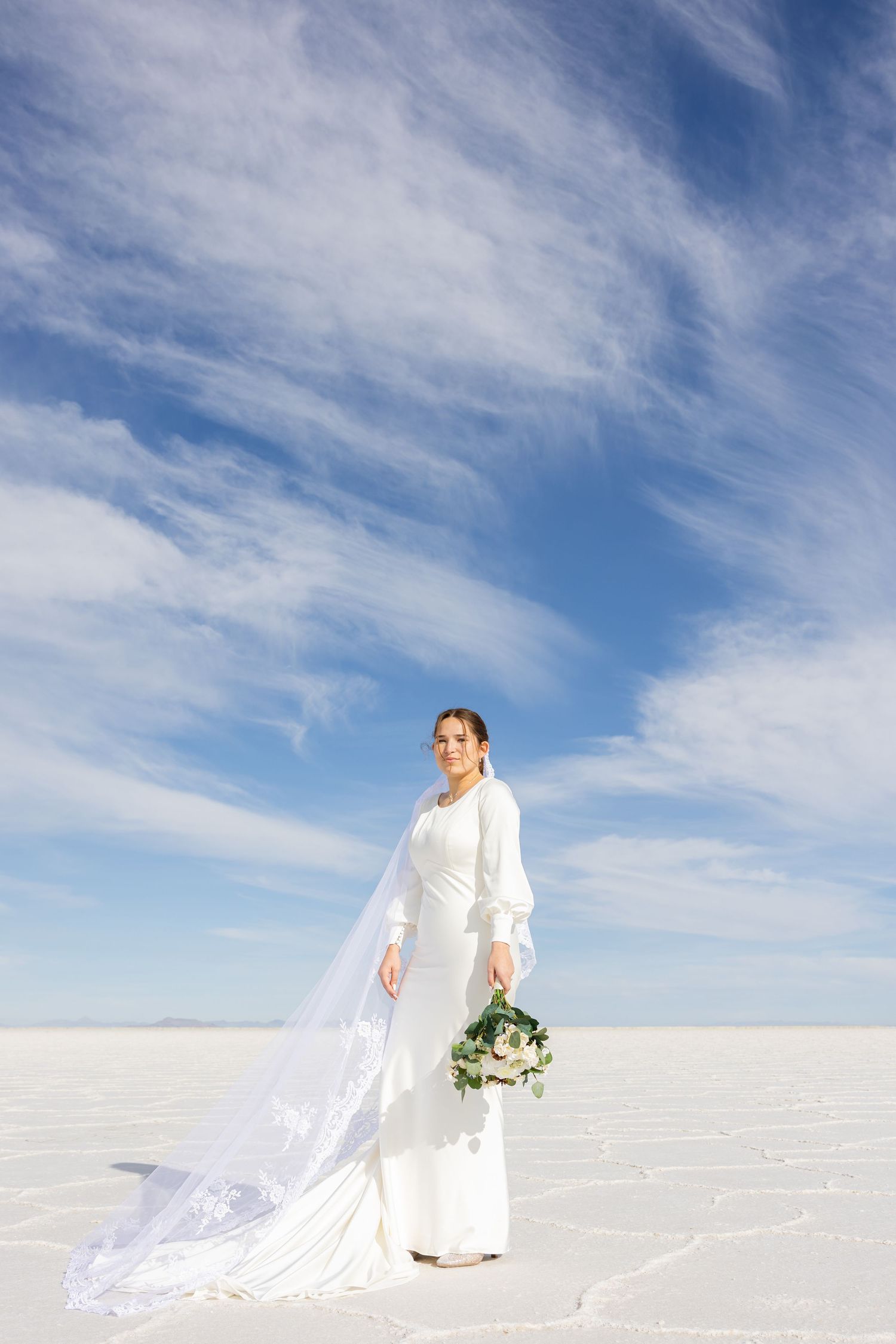 Wedding couple walking on pristine white snow under bright blue skies.