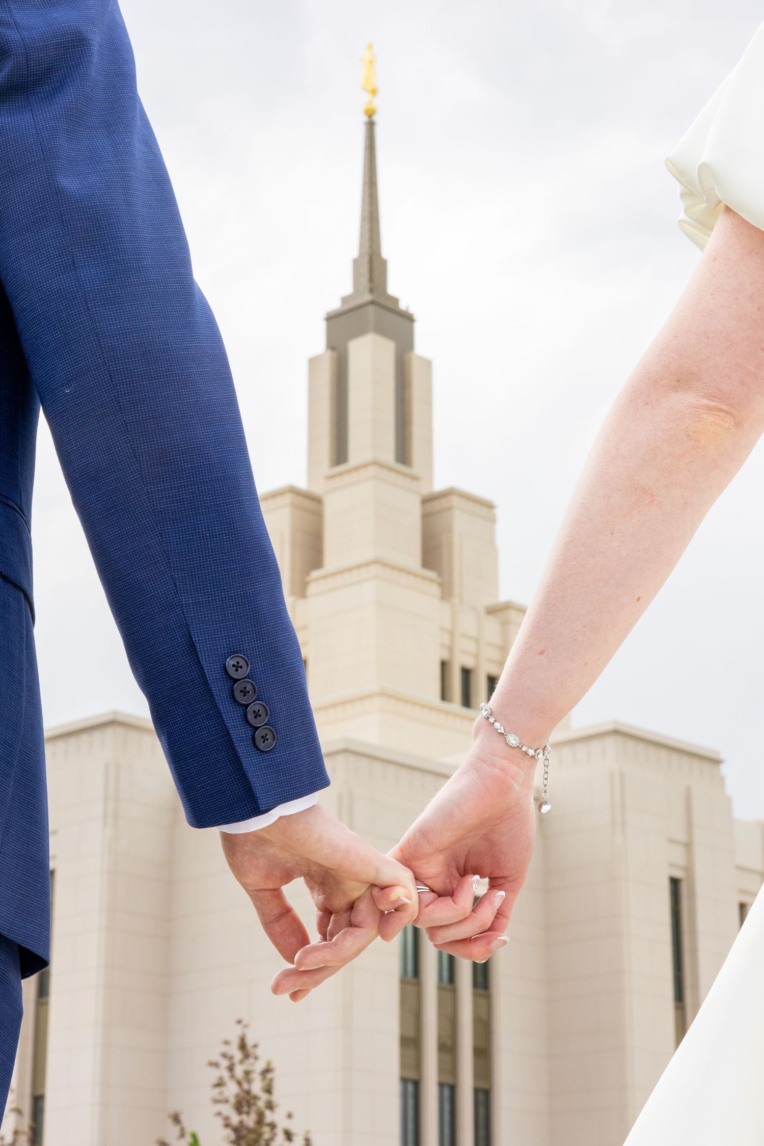 Close-up of joined hands with temple spires rising in background.