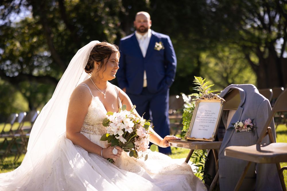 A couple signs marriage documents at an outdoor wedding ceremony in a garden setting.