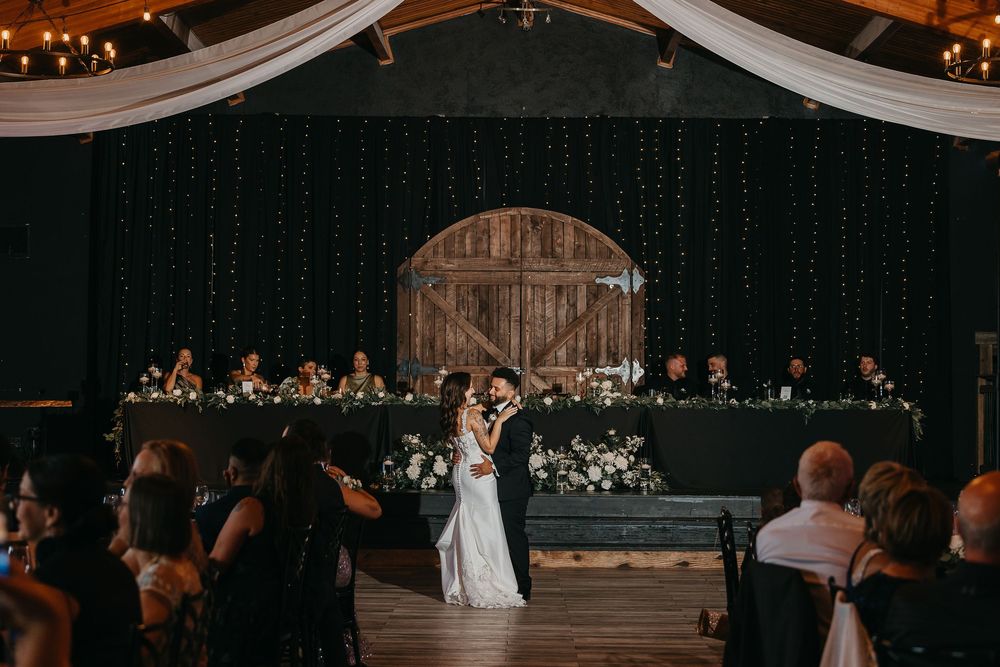Wedding reception venue decorated with elegant white drapes and warm lighting creates a romantic atmosphere.
