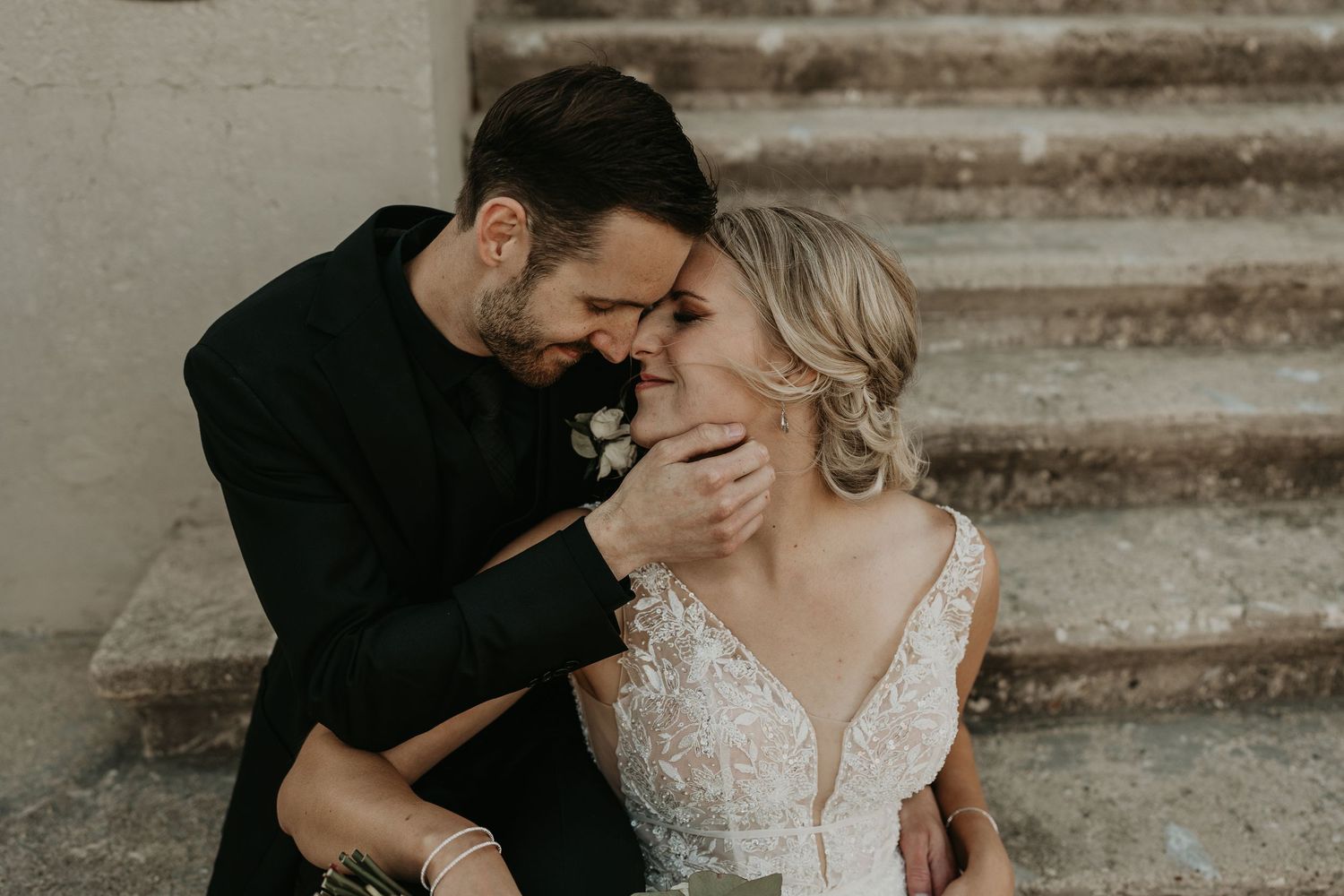 groom nuzzling bride as they sit on concrete stairs in walkerton Ontario