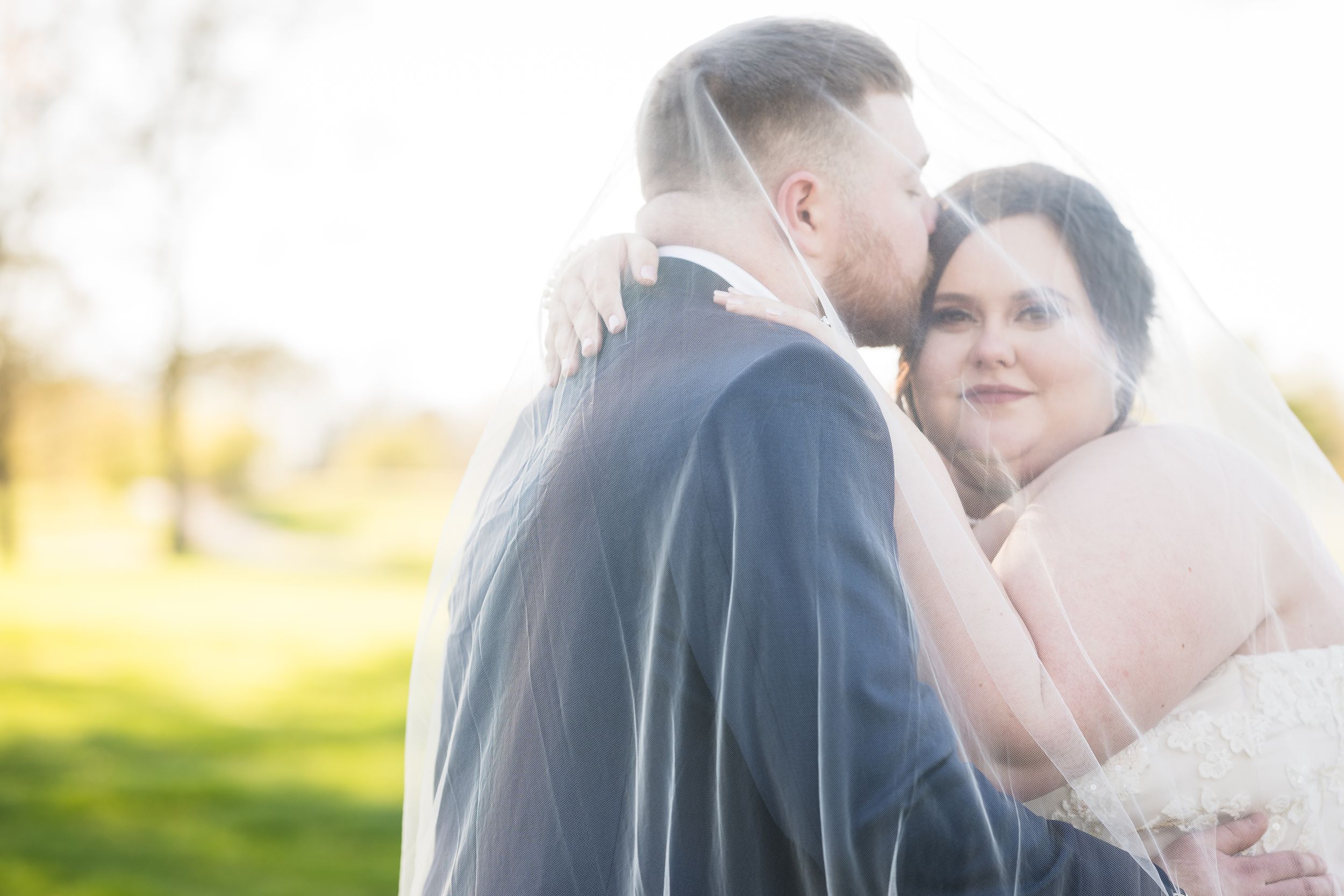 A tender moment between newlyweds during their outdoor wedding photoshoot.