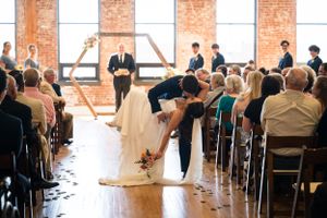 Wedding ceremony in a rustic brick venue with guests watching the couple's first kiss.