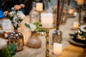 Elegant wedding table decor with gold candle holders, white candles, and blush floral arrangements.