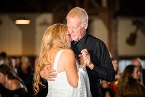 Father and daughter share an emotional first dance at a rustic barn wedding reception.