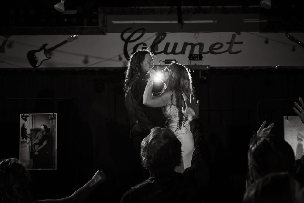 Black and white photo of two performers embracing on stage at Calumet venue with crowd cheering.