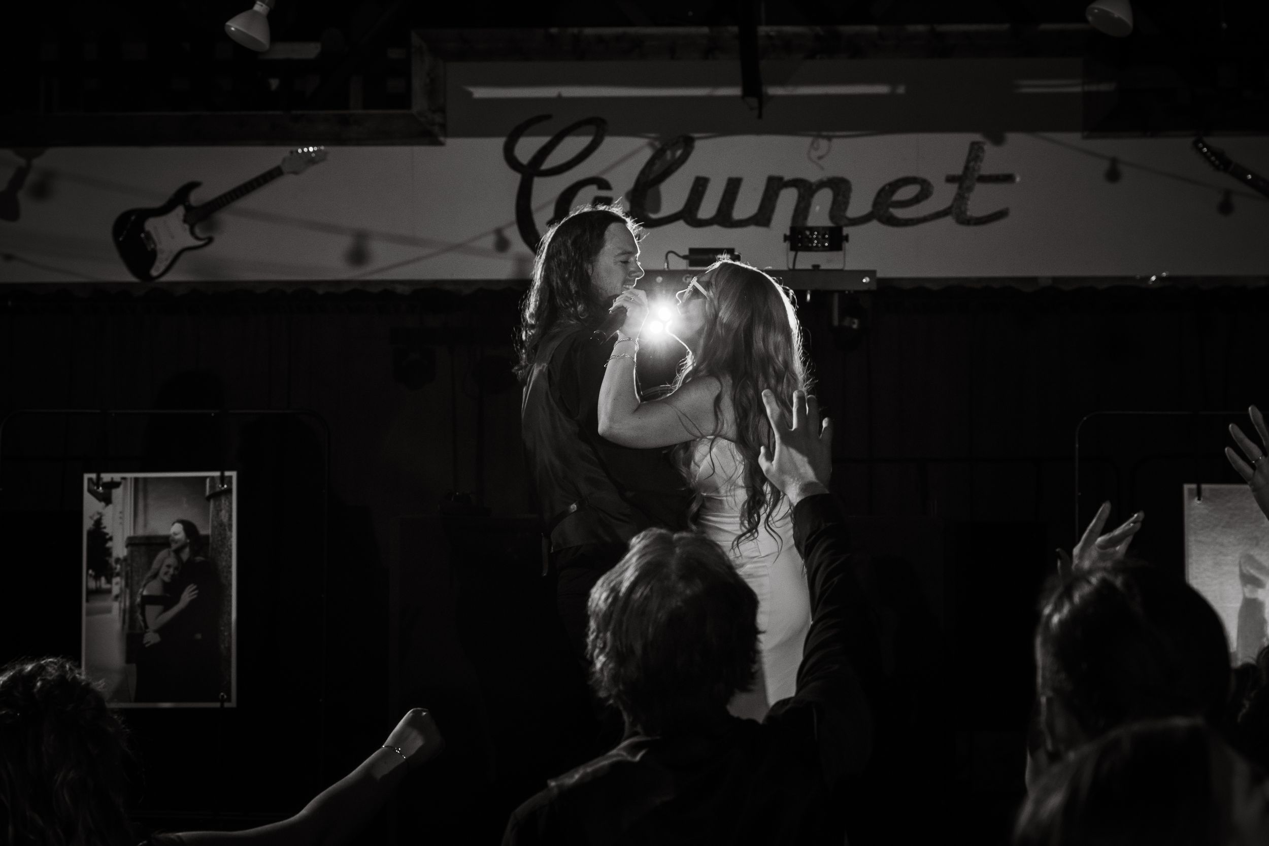 Black and white photo of two performers embracing on stage at Calumet venue with crowd cheering.