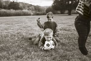 Black and white photo sequence showing someone rolling down a grassy hill in a playful tumbling motion.