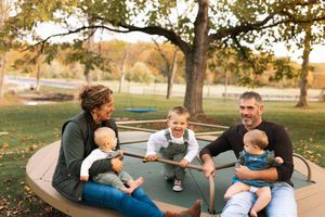 Family members share joyful moments together while playing and relaxing outdoors in a park setting.