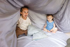 A series of photos showing a toddler playing and lounging on a white bed with natural light streaming in.
