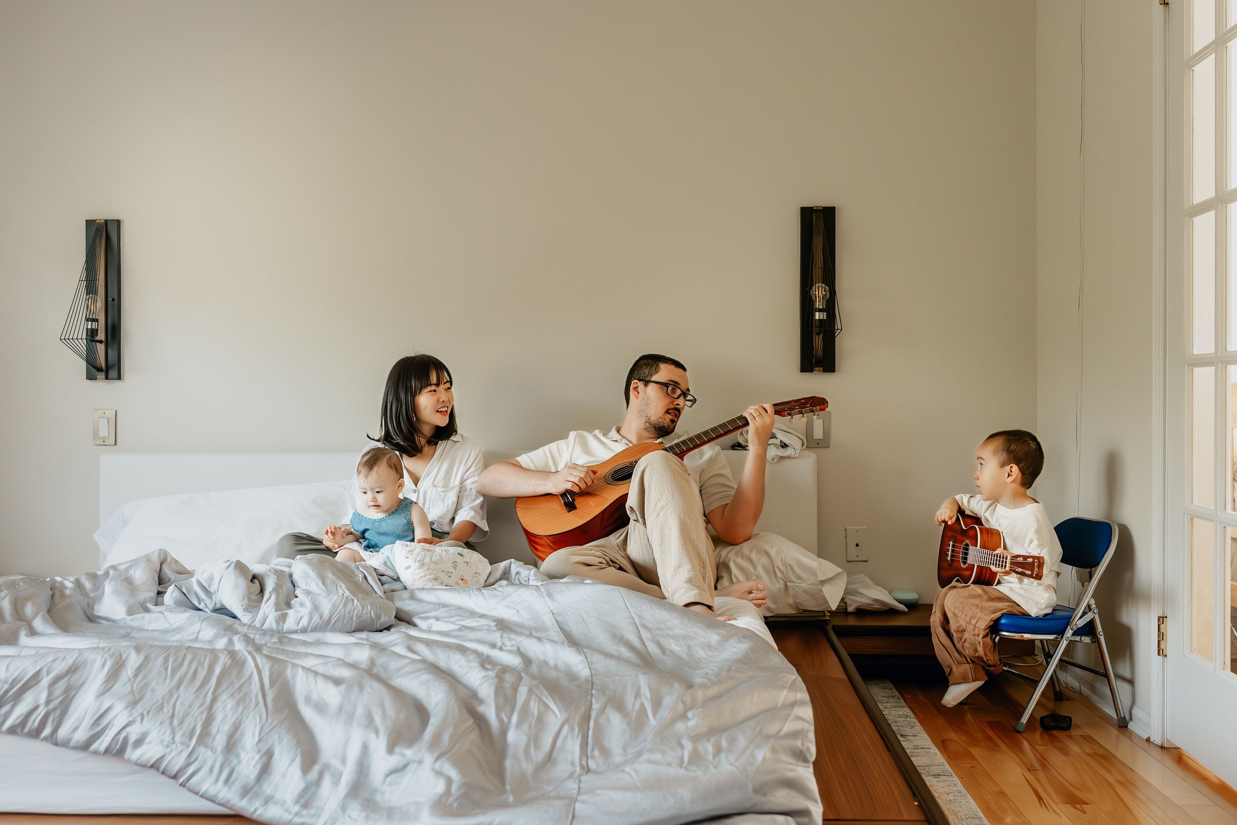 Multiple shots of a child playing and relaxing on a large bed in a minimalist white room.