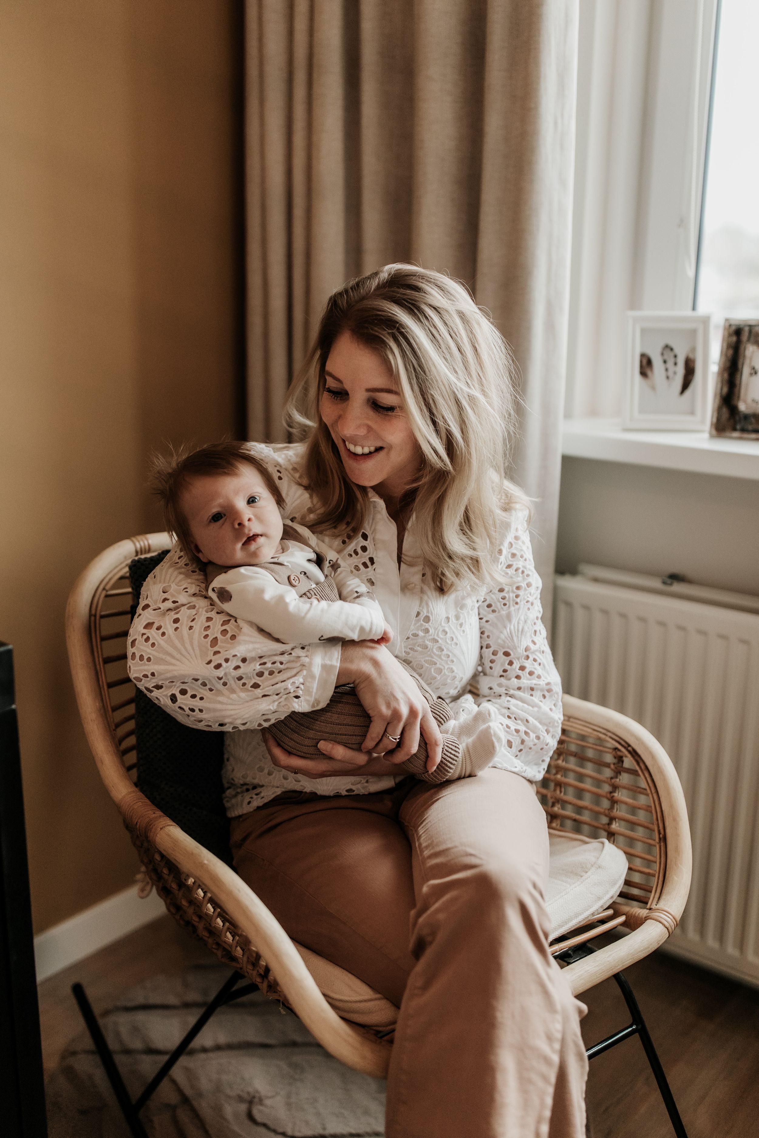 Moeder zit op een stoel en knuffelt haar newborn baby