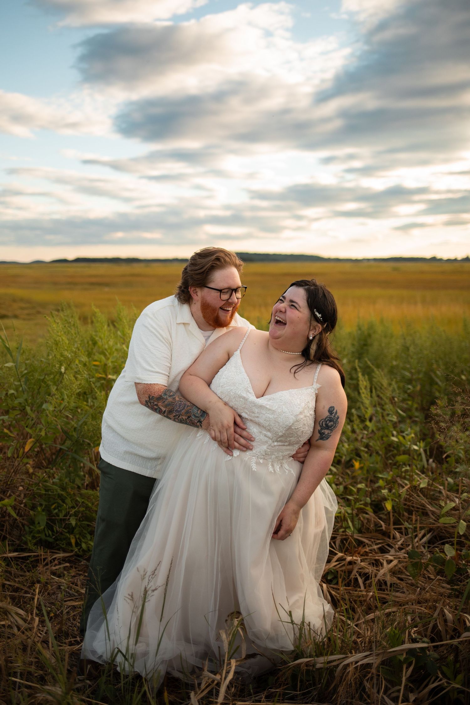 Authentic wedding photography in Rhode Island showing a groom laughing with his bride during an unscripted moment in a field.